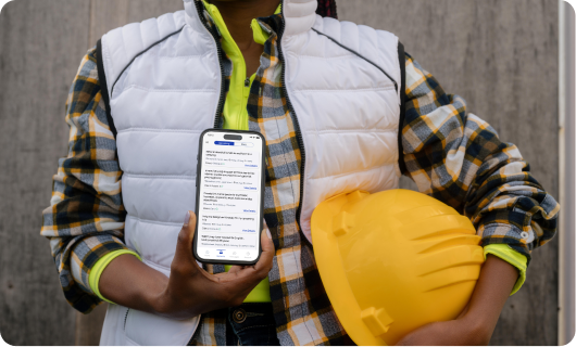 A construction worker in a hard hat holding a phone running the Hustle app